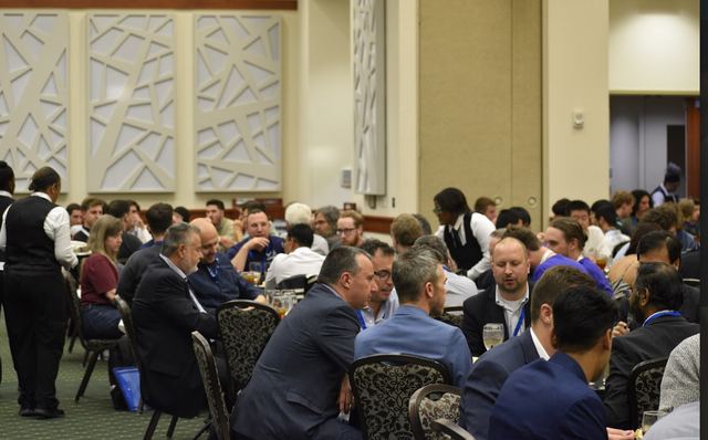 Conference attendees seated at round tables in a ballroom.