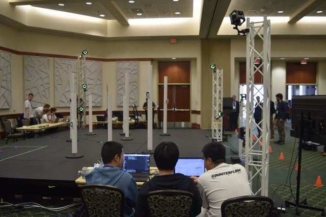 A testbed control area with staff working at laptops beneath an overhead truss structure.